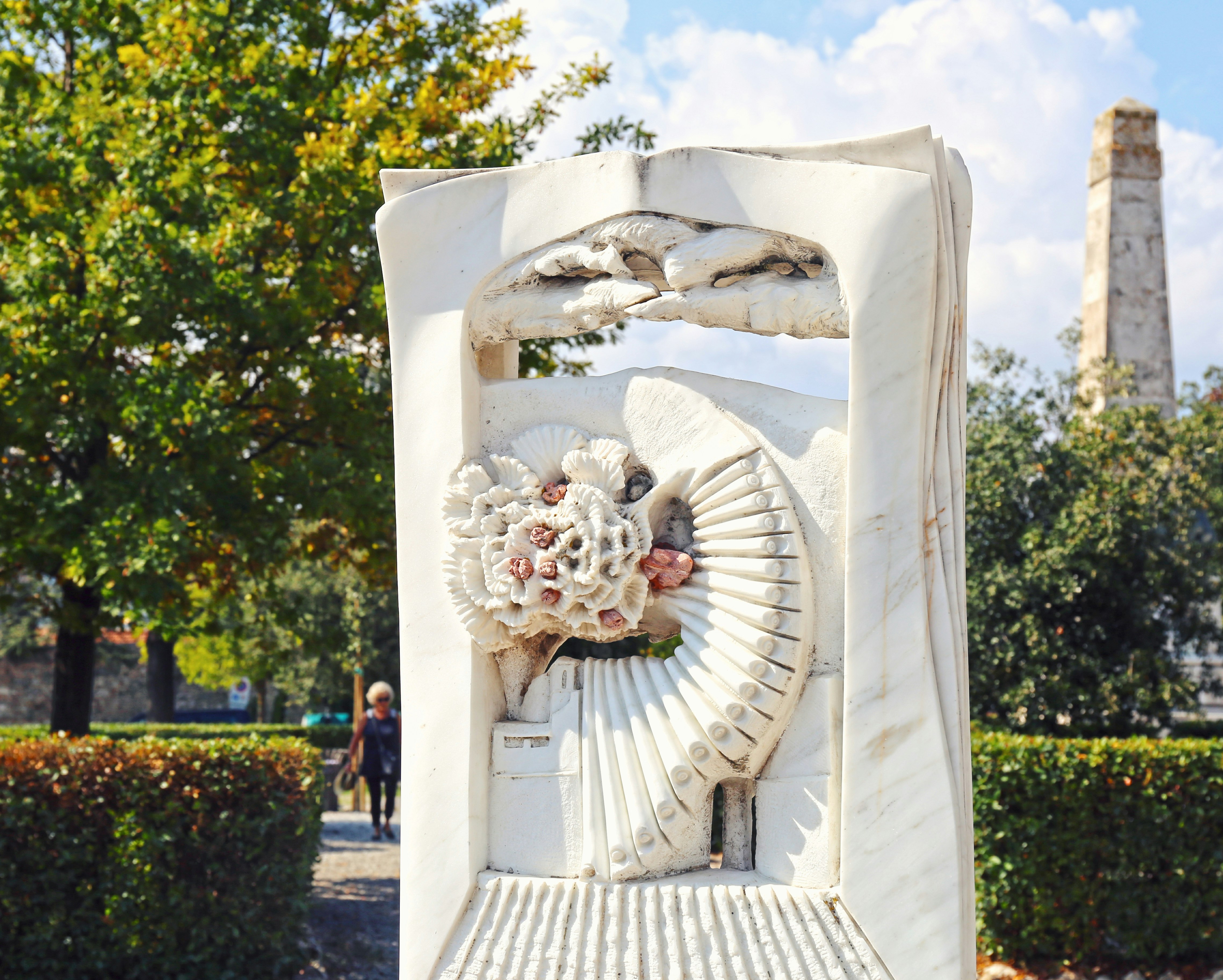 white concrete statue near green trees during daytime